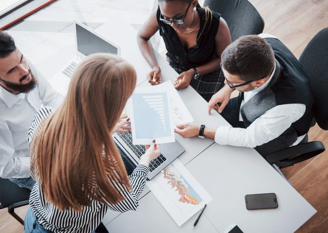 Young employees sitting in the office at the table and using a laptop, a team work brainstorming meeting concept