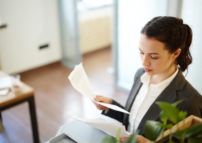 Young manager reading business papers or contracts in office