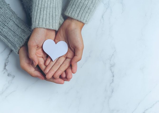 paper heart put in couple's hands on marble table