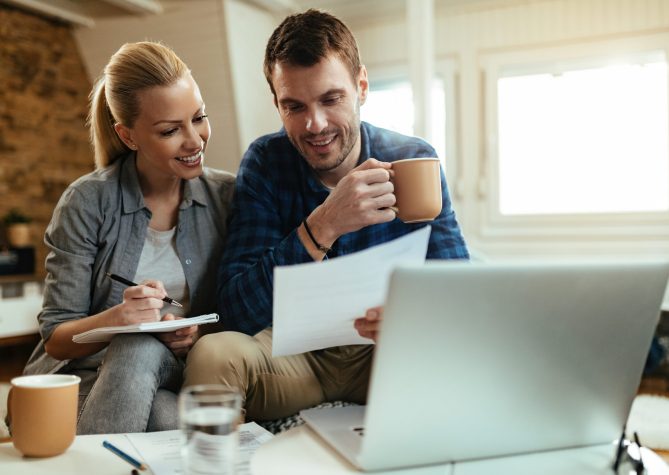 Happy couple going through paperwork while working together at home.