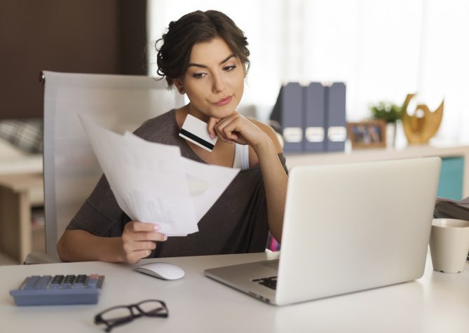 Pensive woman paying bills at home